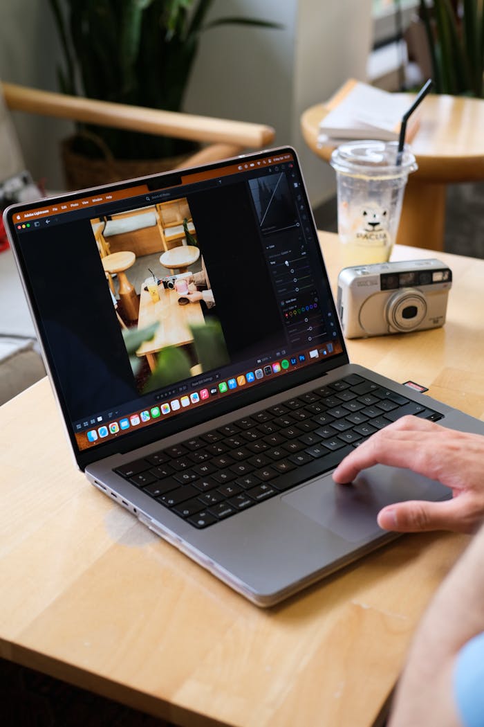 Person edits photo on laptop in a cozy café, capturing creative digital work vibe.