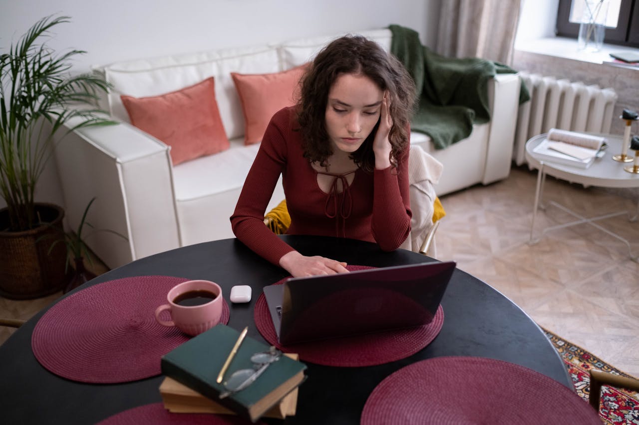 Young woman focused on laptop work with a cup of coffee in a cozy home setting.